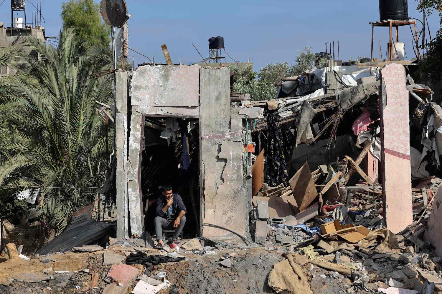 Palestinians inspect their belongings amidst the rubble of their house at Nusseirat refugee camp in Gaza, on May 14, 2023, amid a ceasefire. (AFP)
