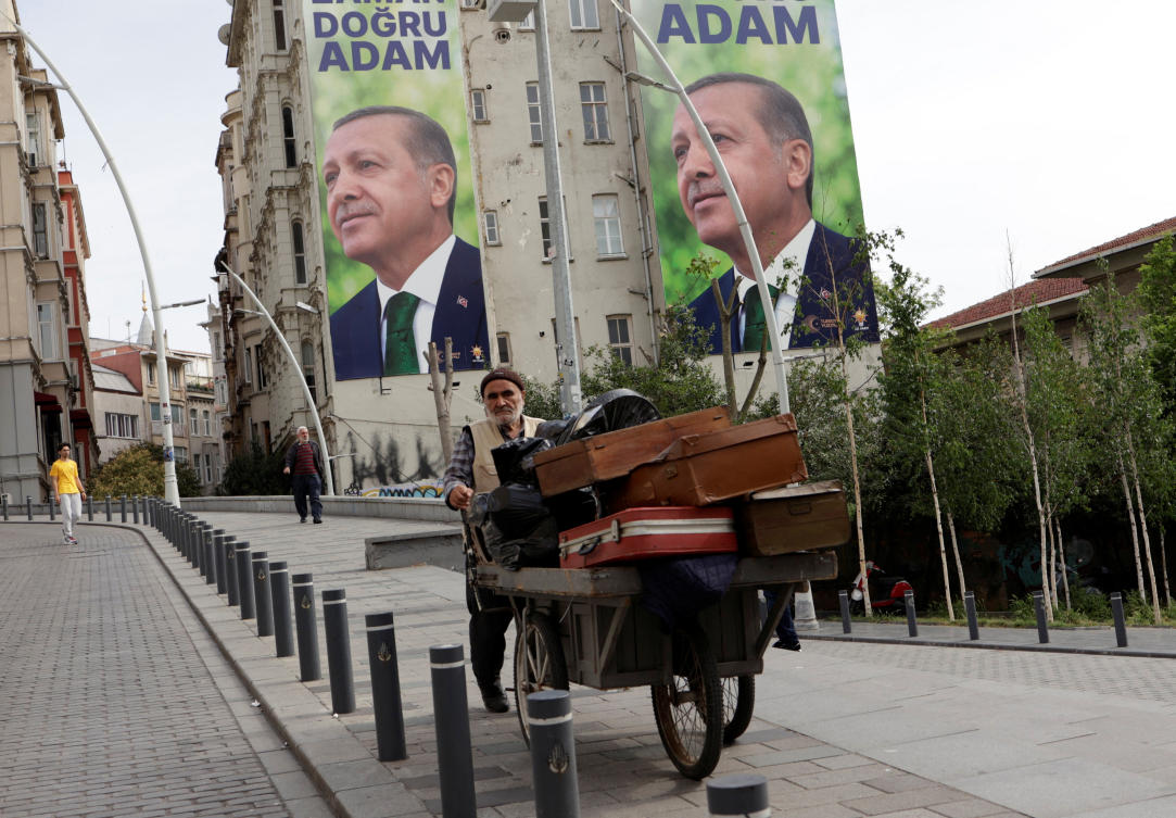A vendor makes his way in a street, with election campaign posters of Turkish President Tayyip Erdogan in the background, following the first round of presidential and parliamentary elections, in Istanbul. (File/Reuters)