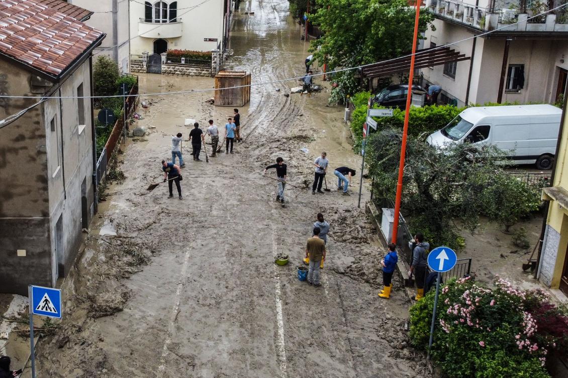 An aerial view taken on May 18, 2023 shows residents clearing mud in a street of Cesena after heavy rains caused flooding across Italy’s northern Emilia Romagna region, killing five people. (AFP)