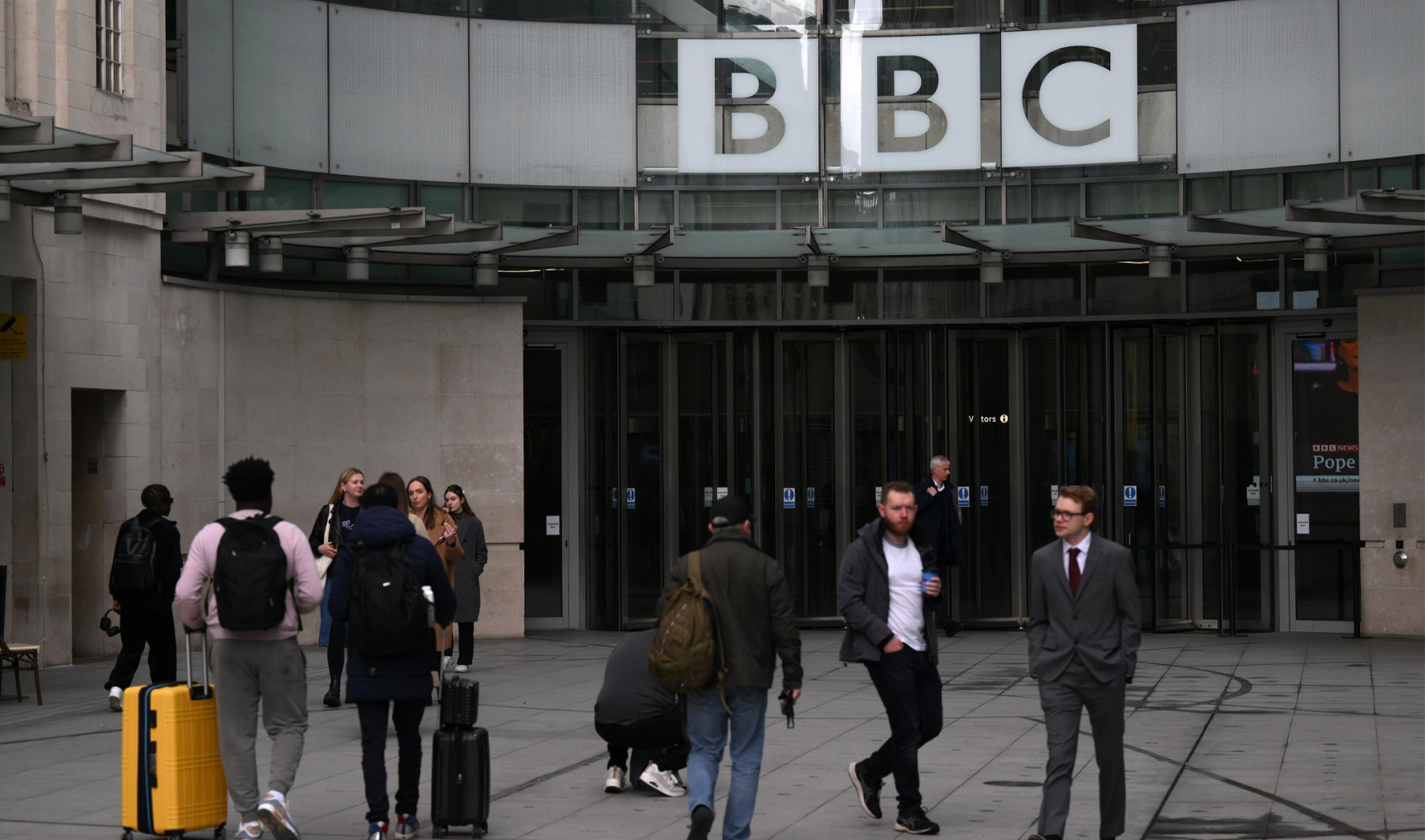 People use the front entrance of the headquarters of the British Broadcasting Corporation (BBC) in London on April 28, 2023, on the day the BBC chairperson Richard Sharp resigned. Sharp announced his resignation on April 28, 2023 over involvement in securing a private credit line for up to £800,000 ($990,000) for the then-PM Boris Johnson from a Canadian businessman. (AFP)