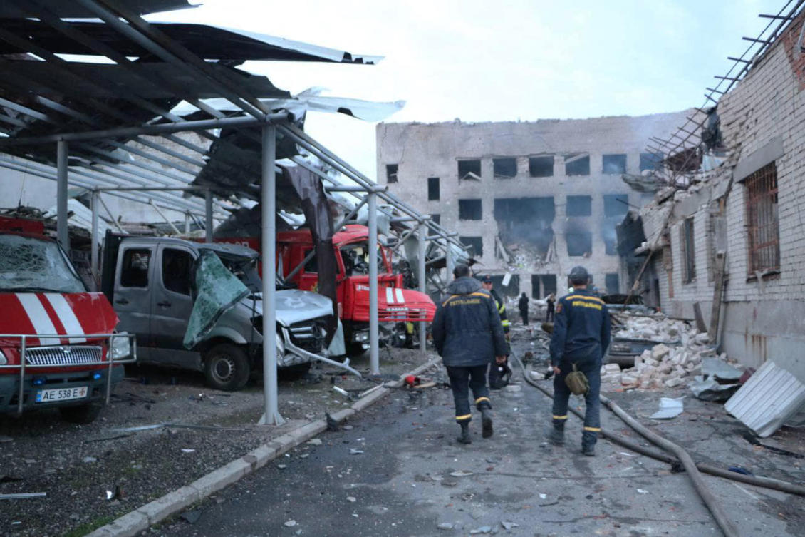 Ukrainian rescuers walk past damaged emergency service trucks next to a damaged fire station after a strike in the eastern Ukrainian city of Dnipro, amid the Russian invasion of Ukraine. (AFP)