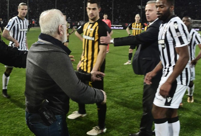 PAOK president Ivan Savvidis, left, takes to the pitch carrying a handgun in his waistband, after the referee ruled out a last minute PAOK goal during the Greek Super League match against AEK Athens in Thessaloniki in March 2018. (AFP/File)