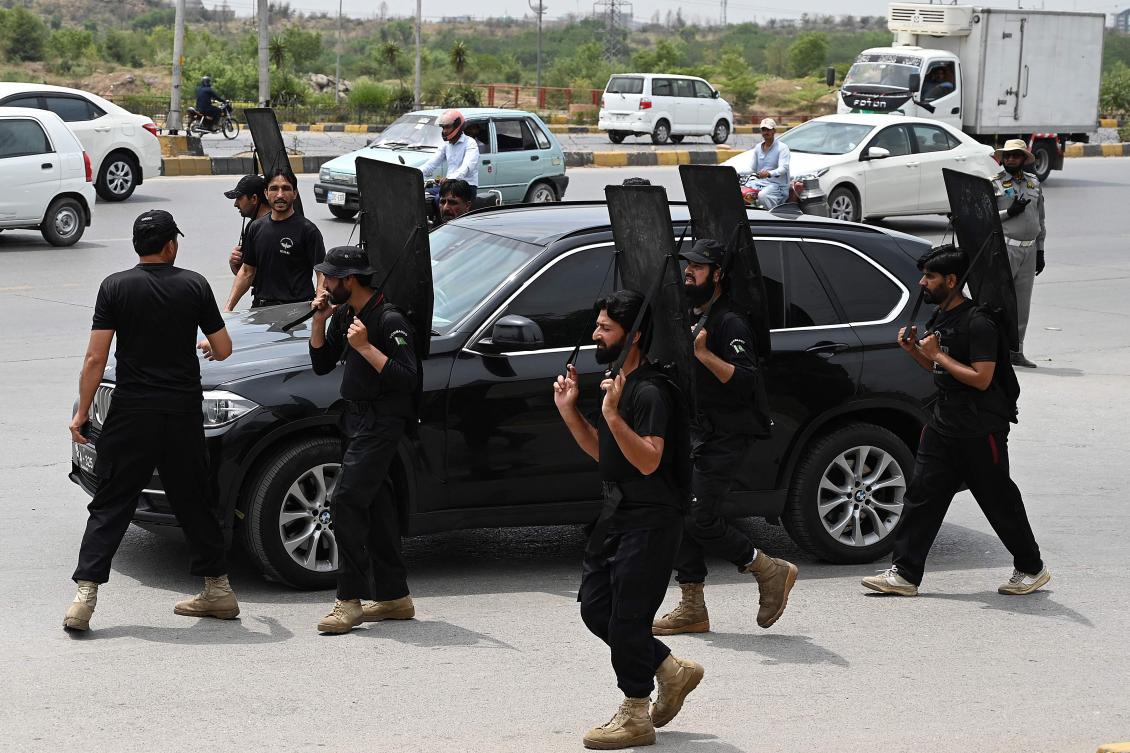 Security personnel with ballistic shields escort a vehicle carrying former Pakistan’s prime minister Imran Khan as he leaves after appearing before an anti-terrorism court in Islamabad on May 23, 2023. (AFP)