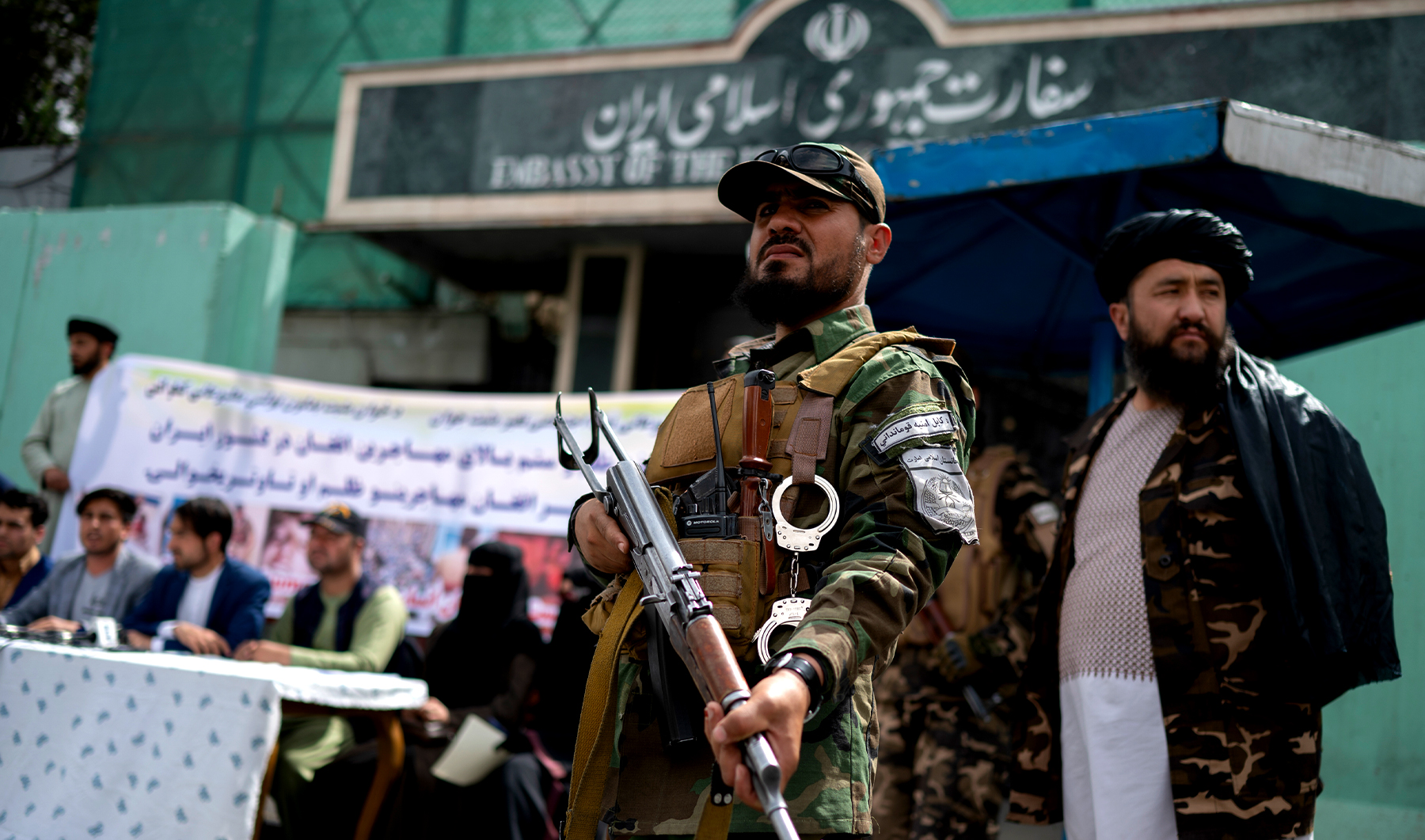 Taliban fighters stand guard as Afghan protestors take part in a protest against the alleged published reports of harassment of Afghan refugees in Iran, in front of the Iranian embassy in Kabul on April 11, 2022. (AFP/File)