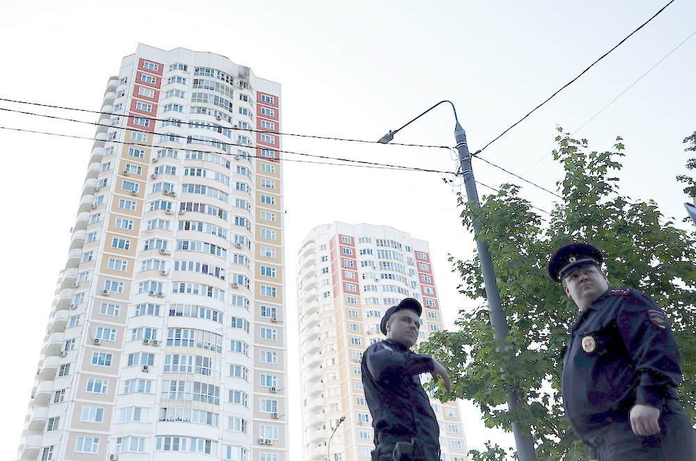 Law enforcement officers stand guard near a damaged multi-storey apartment block following a reported drone attack in Moscow on May 30, 2023. (Reuters)