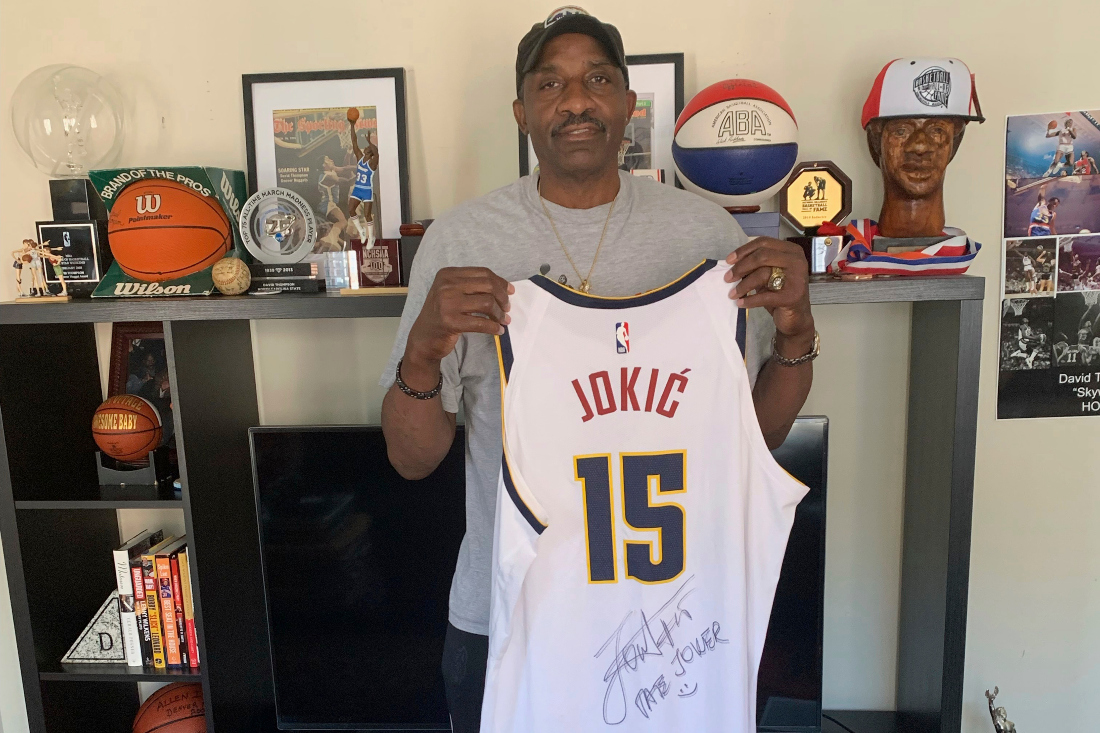 Former ABA/NBA Nuggets great David Thompson holds up a jersey of two-time MVP Nikola Jokic at his home in Charlotte, N.C. Thompson is a big fan of Jokic and the Nuggets as they get set to play in their first NBA Finals. (AP)