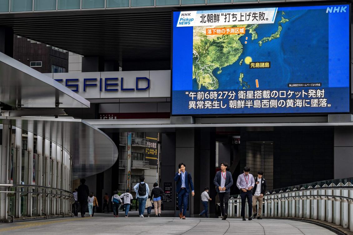 Pedestrians walk past a large video screen showing a map of the region during a news update in Tokyo after North Korea launched a spy satellite that crashed into the sea. (AFP)