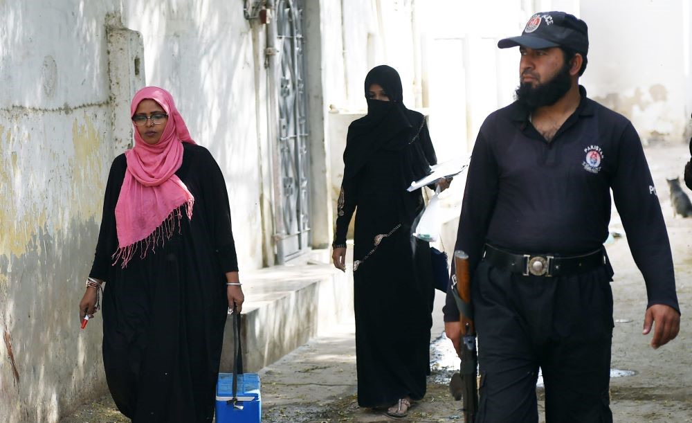 A Pakistani policeman guards a team of polio vaccinators during an immunization drive in Karachi, Jan. 22, 2018. (AFP)