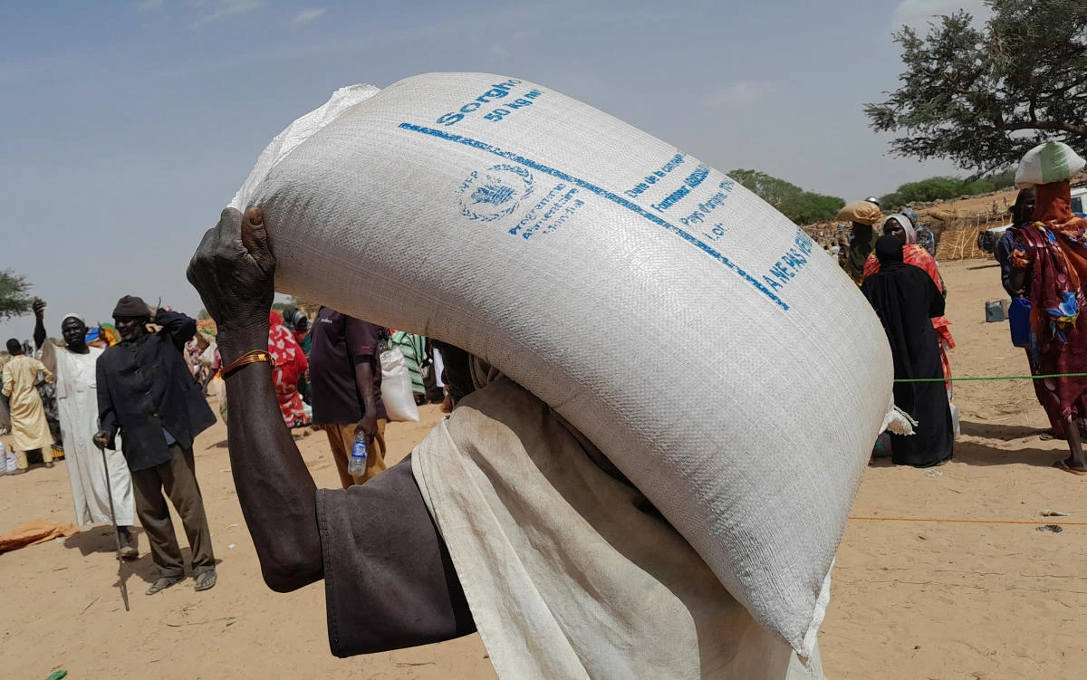 A worker of World Food Programme (WFP) carries a bag of relief grains to be distributed to Sudanese refugees who have fled the violence in their country, near the border between Sudan and Chad, in Koufroun, Chad April 28, 2023. (Reuters)