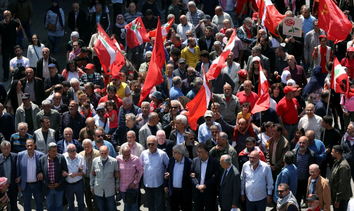 People carry flags and banners as they march during a demonstration organized by the Lebanese Communist Party to mark Labour Day, in Beirut, Lebanon May 1, 2023. (Reuters)