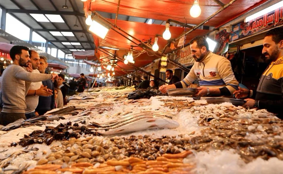 An Egyptian vendor shows different kinds of fish to customers at the new fish market at Port Said city, northeast of Cairo, Egypt, Jan. 5, 2023. (Reuters)