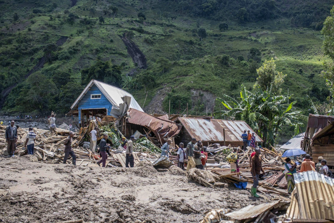 People walk next to houses destroyed by the floods in the village of Nyamukubi, South Kivu province, in Congo on May 6, 2023. (AP)