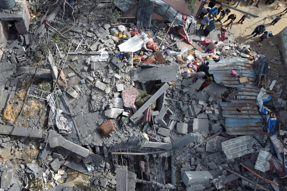 In this aerial picture people sift through the rubble of a building hit in an Israeli air strike in Beit Hanun, in the northern Gaza Strip (AFP)