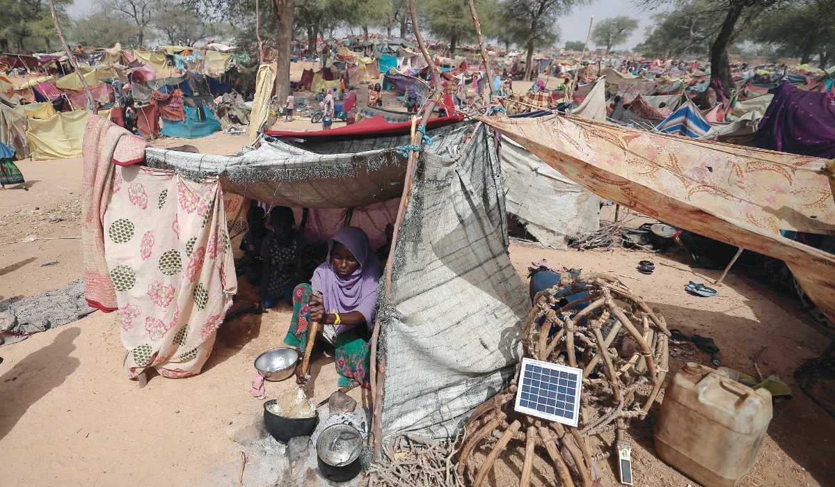 A woman, who fled the conflict in Darfur region, cooks at her makeshift shelter on Saturday near the border between Sudan and Chad. (Reuters)