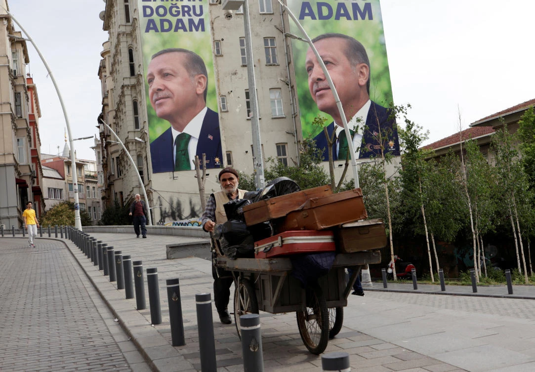 A vendor makes his way in a street, with election campaign posters of Turkish President Tayyip Erdogan in the background, following the first round of presidential and parliamentary elections, in Istanbul. (File/Reuters)