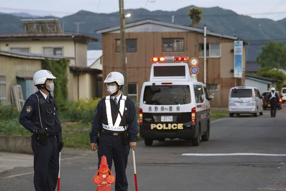 Above, police officers stand guard on a street leading to a building where a man is holed up in Nakano, central Japan on May 25, 2023. (Kyodo News via AP)