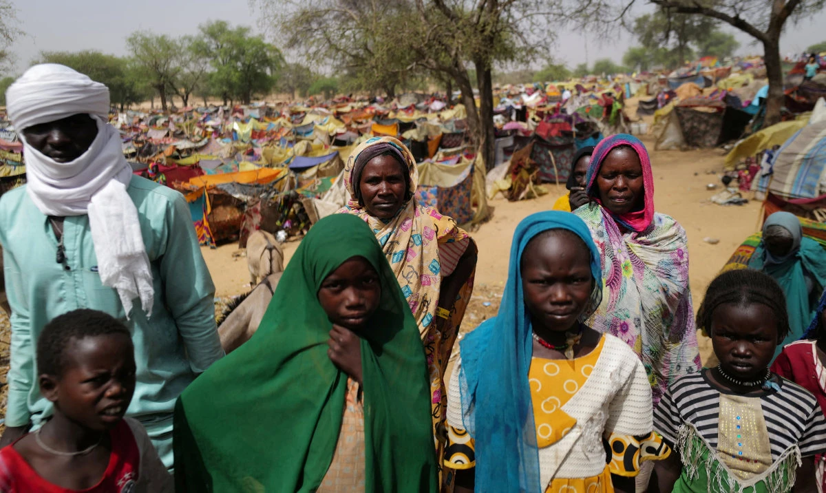 Sudanese people who fled the conflict in Sudan's Darfur region, look on as they stand near makeshift shelters. (Reuters)