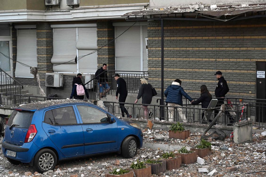 A policeman escorts local residents to collect their belongings in their multi-story residential building, partially destroyed after night drone attacks in Kyiv. (AFP)
