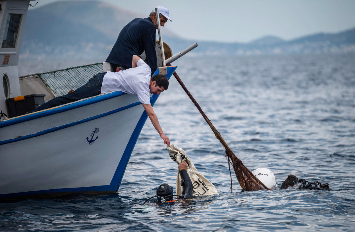 Divers and volunteers collect ghost nets under the water during a cleanup operation near the coast of the Island of Salamina. (AFP)