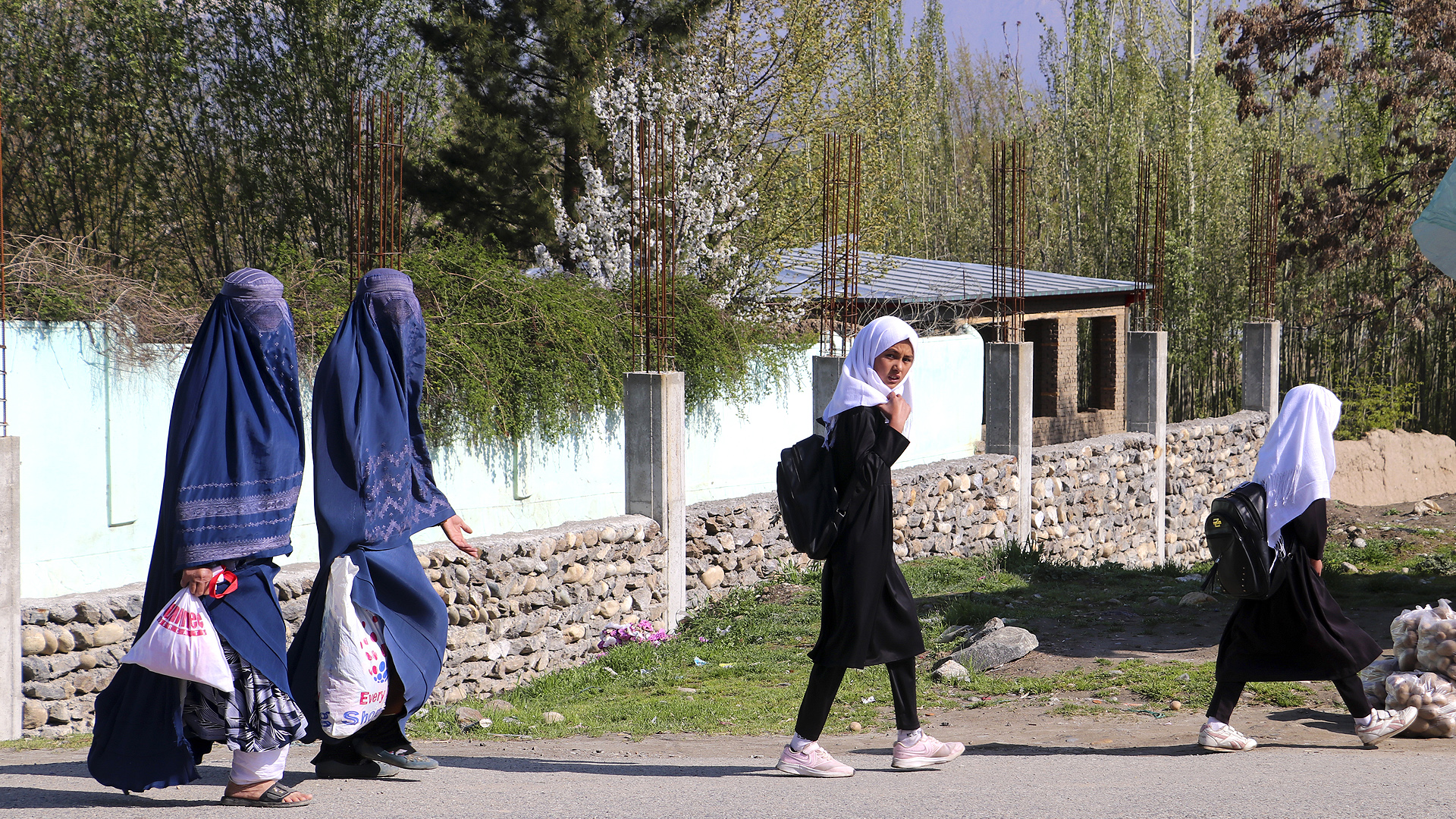 Afghan burqa-clad women along with school girls walk along a road in Fayzabad district of Badakhshan province on March 26, 2023. (Photo courtesy: AFP)