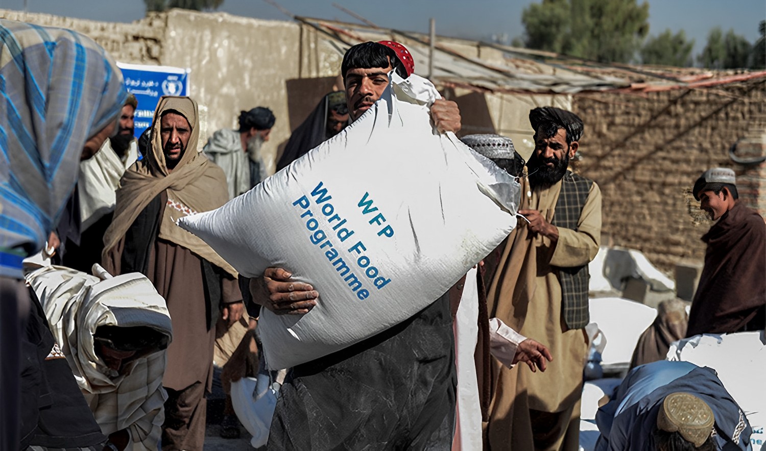 Afghan people carry sacks of food grains distributed as an aid by the World Food Programme (WFP) in Kandahar on October 19, 2021. (AFP)