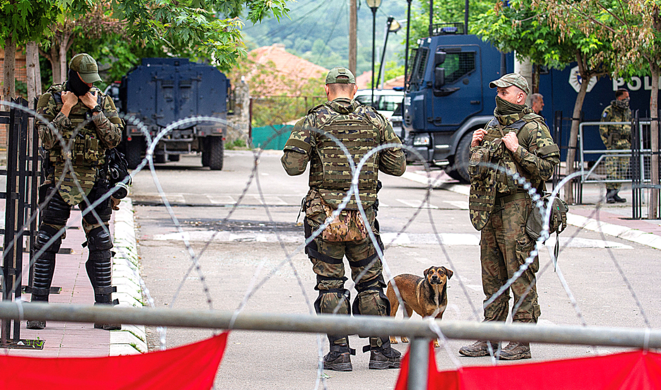 NATO Kosovo Force, or KFOR, soldiers stand guard behind razor wire fence on Monday in the town of Zvecan, Kosovo. (Reuters)