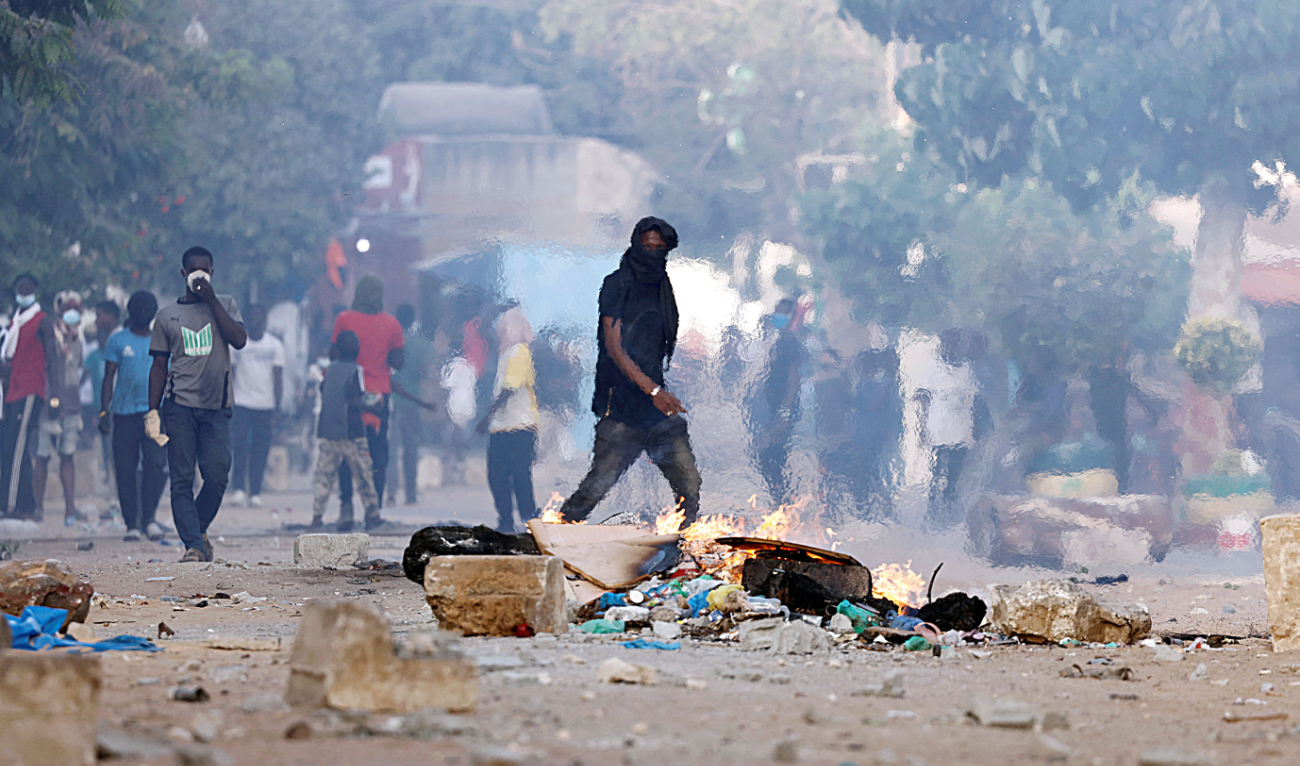 A supporter of Senegal opposition leader Ousmane Sonko walks near a burning barricade during clashes with security forces in Dakar. (Reuters/File)