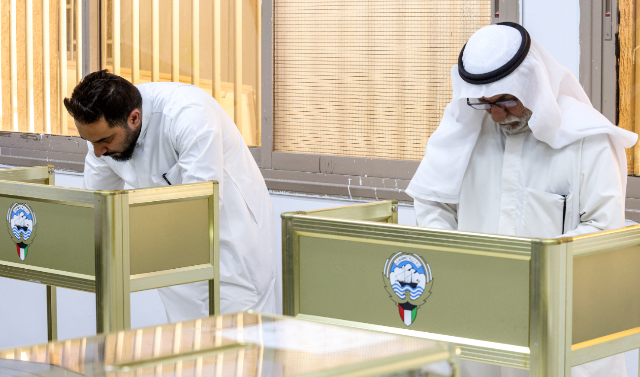 Voters tick their ballots at a polling station during parliamentary elections in Kuwait City on June 6, 2023. (AFP)