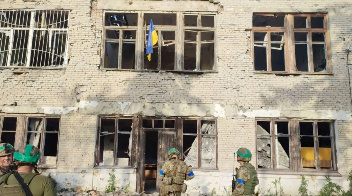 Ukrainian soldiers stand in front of a building with a Ukrainian flag on it, during an operation that claims to liberate the first village amid a counter-offensive, in a location given as Blahodatne, Donetsk Region, Ukraine, in this screengrab taken from a handout video released on June 11, 2023. (REUTERS)
