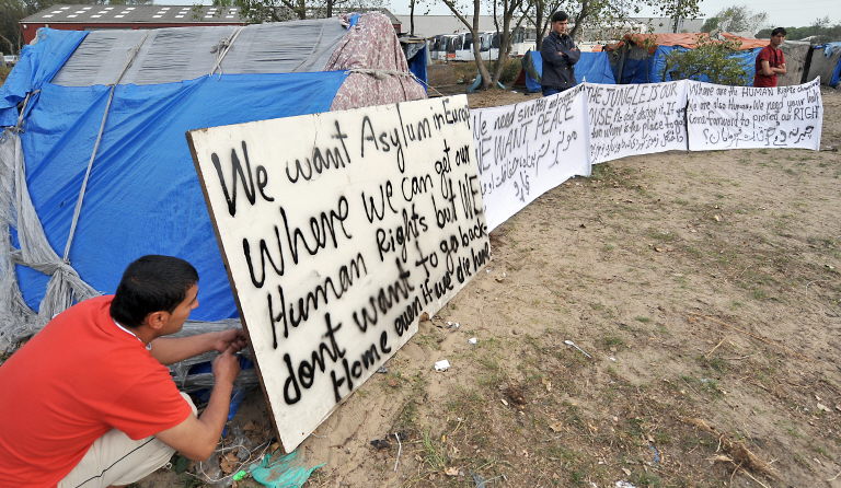 Migrants trying to get to Britain, mostly from Afghanistan, display banners in favour of asylum in Europe, on September 21, 2009 in a wooded area known as "the jungle" in Calais, northern France, where they have set up home. (AFP)