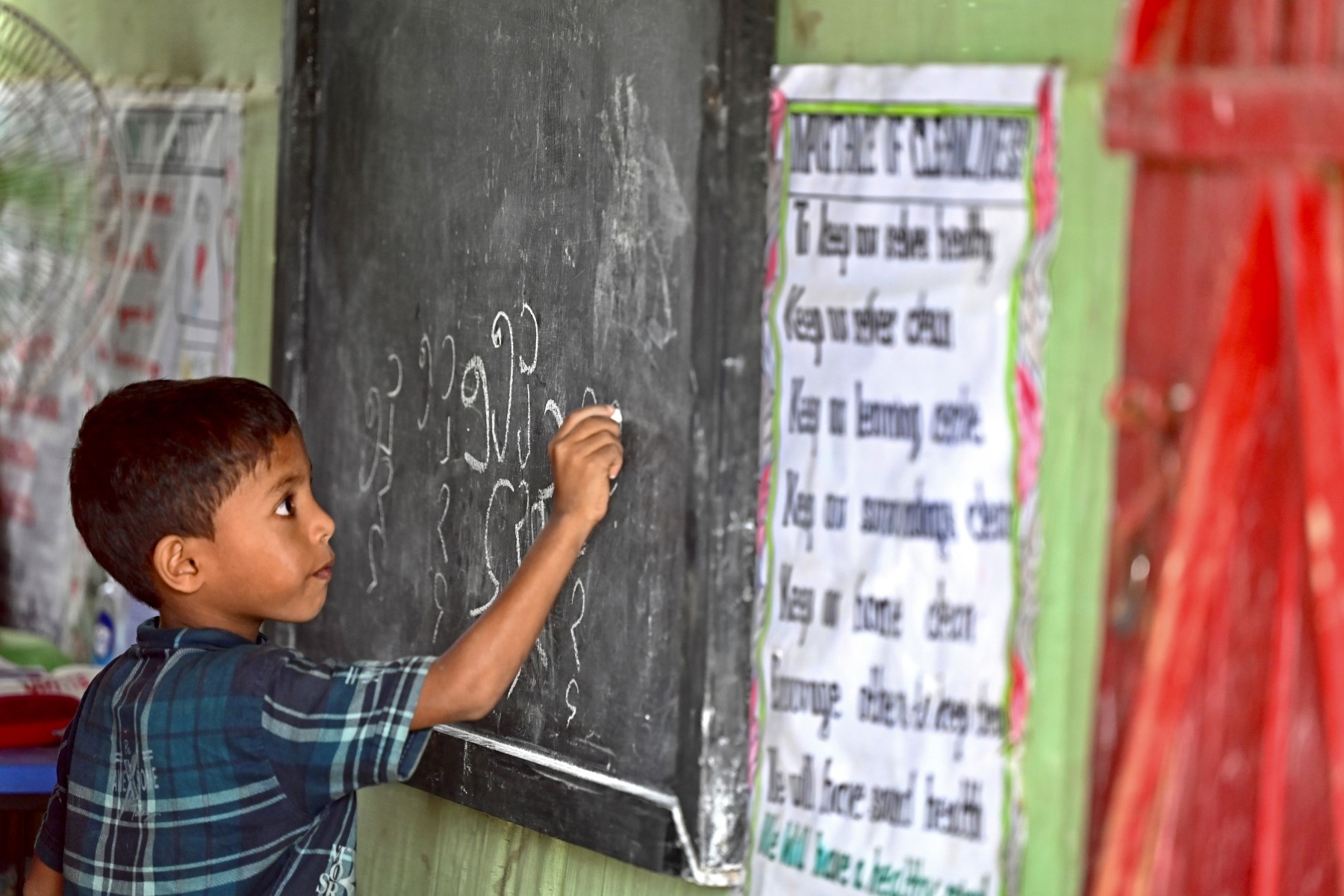 In this file picture taken on Aug. 10, 2022, a Rohingya refugee child writes Rohingya language on a blackboard at a school in Kutupalong refugee camp in Ukhia, Bangladesh. (APF)ro