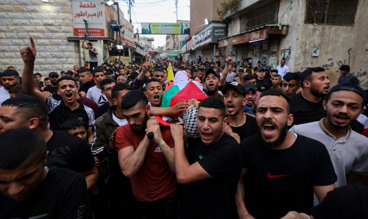 Palestinians carry the body of Faris Hashash, 19, who was killed during clashes with Israeli forces at the Balata refugee camp on the outskirts of Nablus, in the occupied West Bank, during his funeral on June 13, 2023. (AFP)