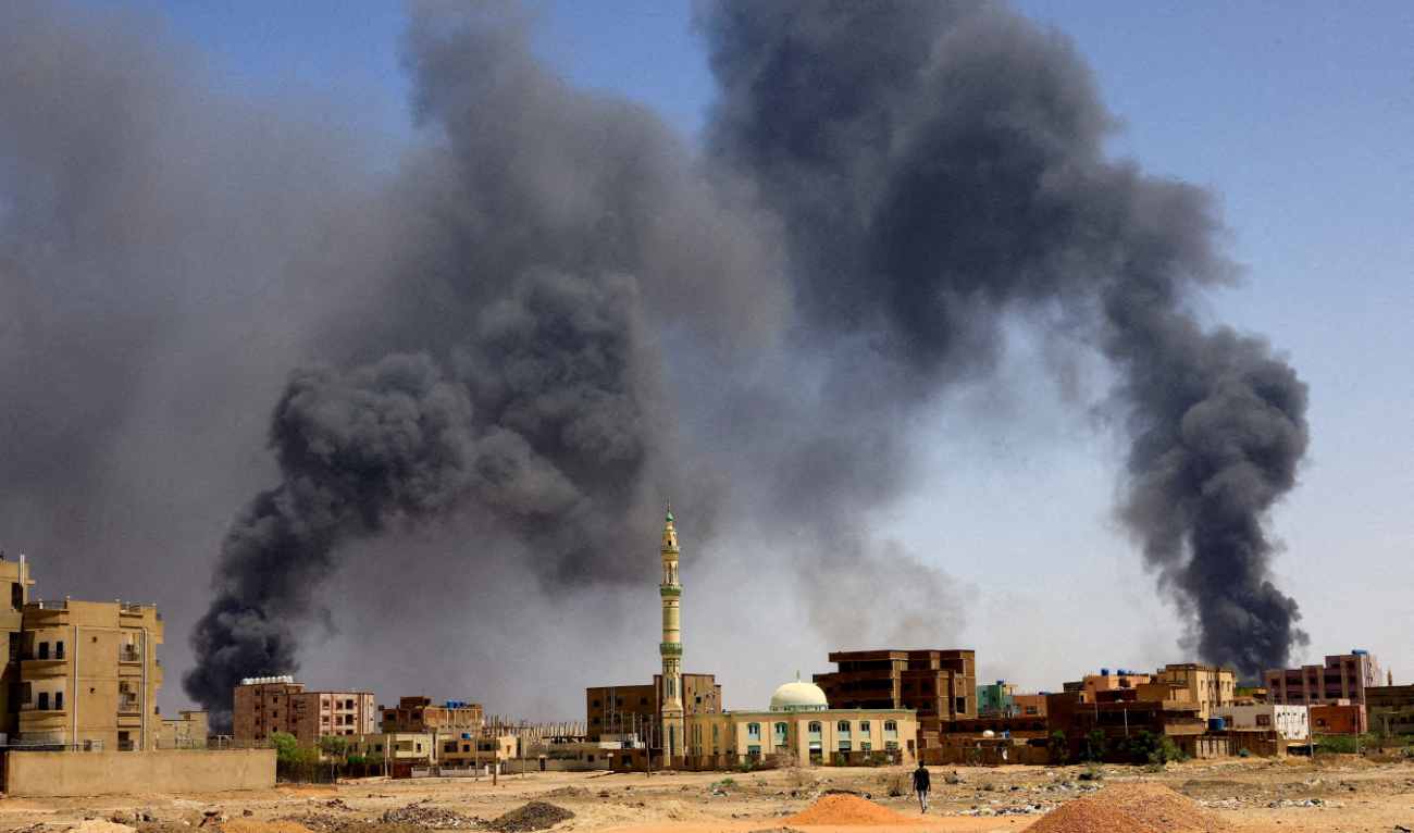 A man walks while smoke rises above buildings after aerial bombardments during clashes between the paramilitary Rapid Support Forces and the army in Khartoum, Sudan, on May 1, 2023. (Reuters)