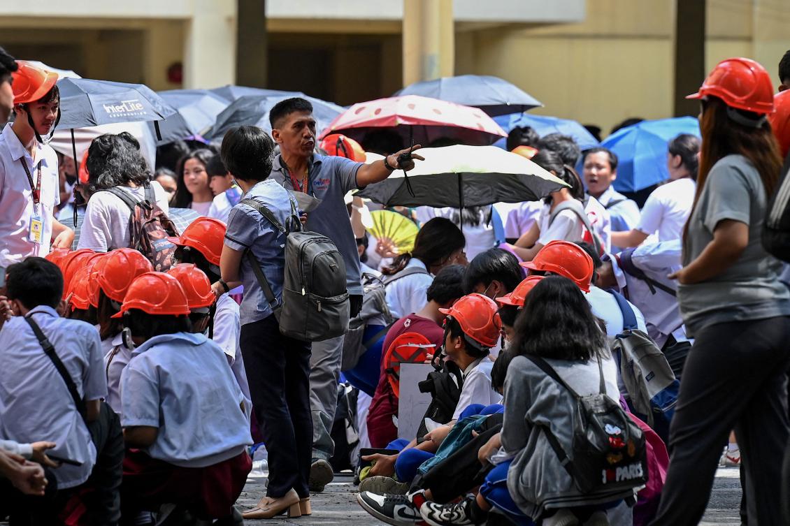 A school staff member instruct students as they evacuate a building in Manila, following a magnitude 6.2 earthquake struck the Philippines. (AFP)