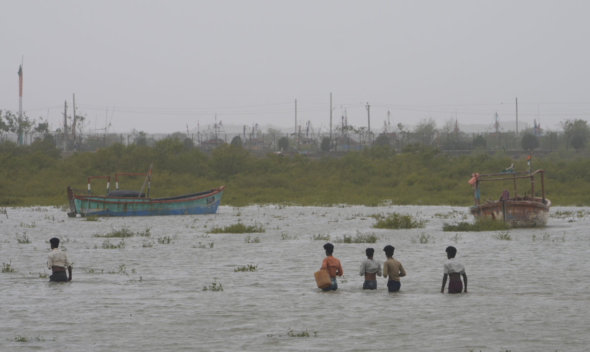 People wade through waist deep water to check on their boats anchored at Jakhau port after landfall of Cyclone Biparjoy at Jakhau in Kutch district of Western Indian state of Gujarat, India, Saturday, June 17, 2023. (AP)