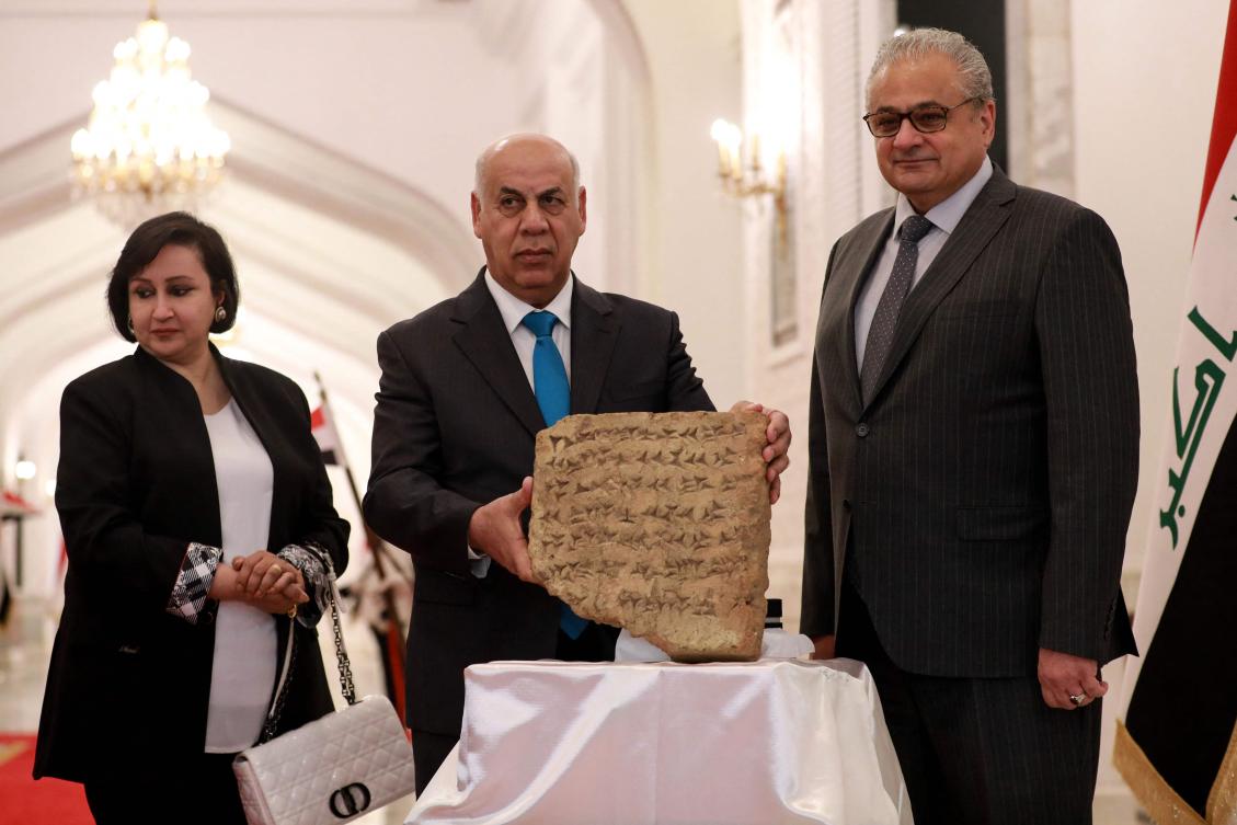 Iraqi Culture Minister Ahmed Fakak al-Badrani (C) and the Director of the Iraqi Council of Antiquities and Heritage Laith Majid Hussein (R) present a 2,800-year-old stone tablet during a press conference in Baghdad, after it was handed over by the Italian authorities to the Iraqi president during his recent visit to Bologna (AFP)