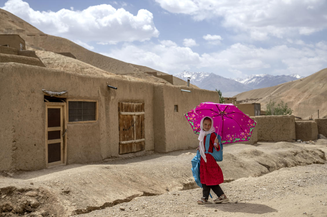A school girl returns home from school while using an umbrella to protect herself from the sun in Bamiyan, Afghanistan, Sunday, June 18, 2023. (AP(