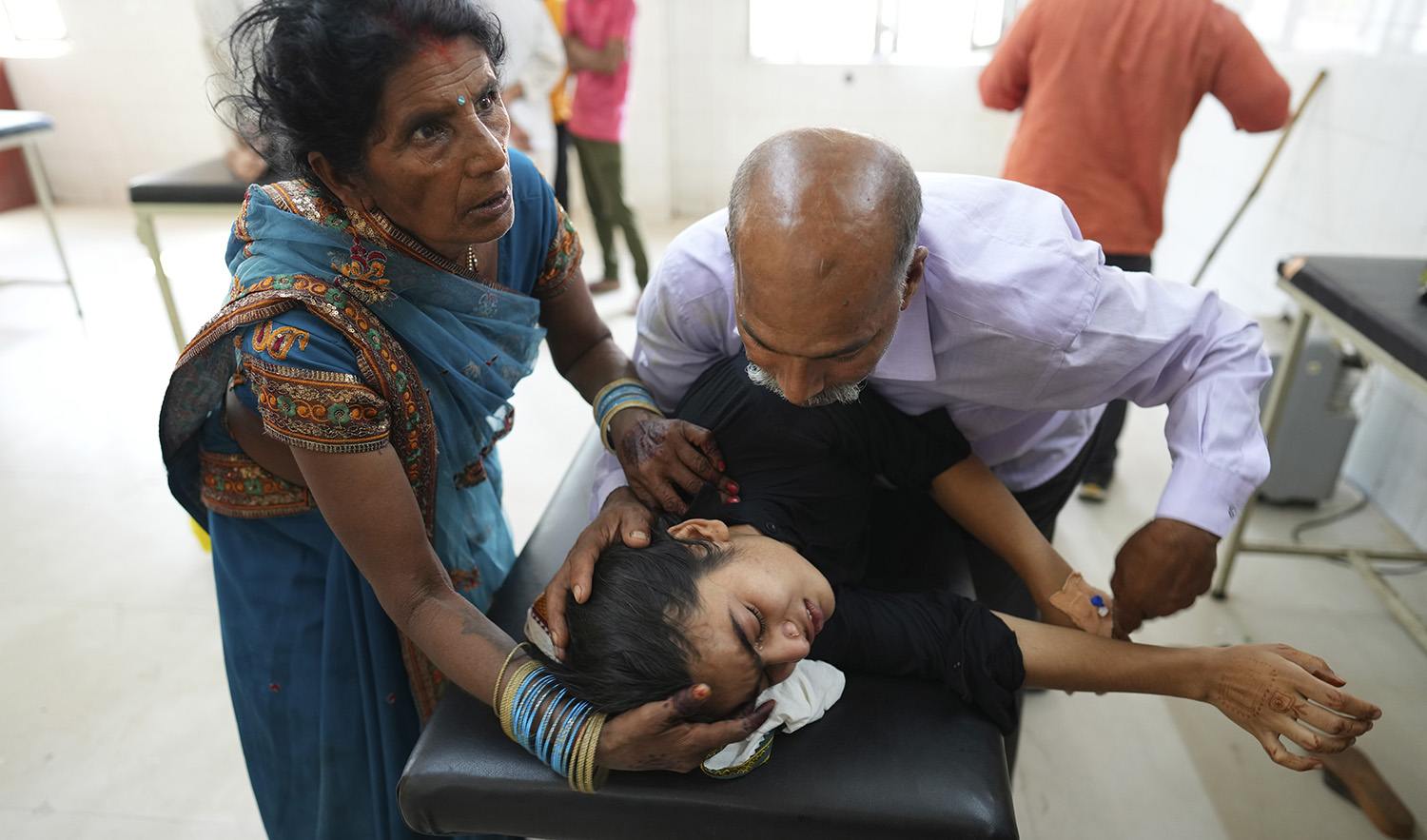 A father tries to pacify his daughter suffering from heat related ailment as she is brought to the government district hospital in Ballia, Uttar Pradesh state, India, on June 19, 2023. (AP)