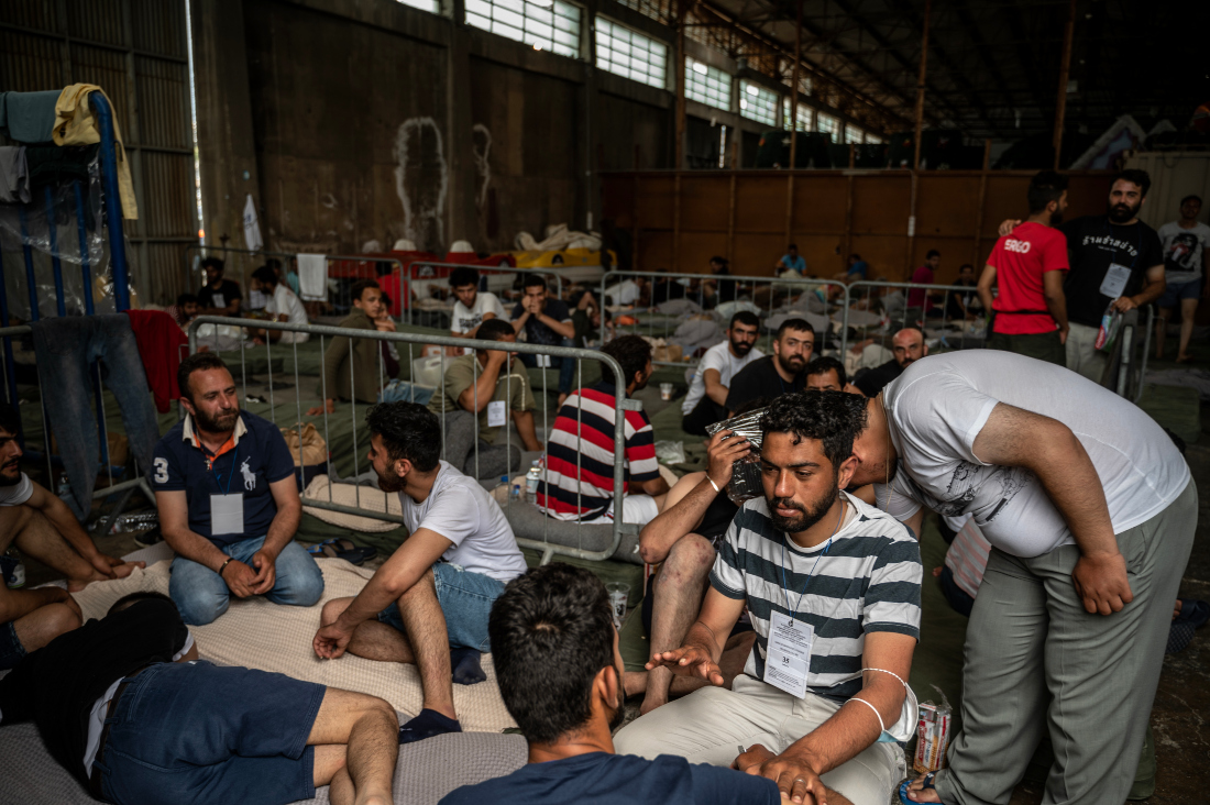 Survivors of shipwreck sit inside warehouse at the port in Kalamata town, after a boat carrying migrants sank in international waters in the Ionian Sea. (File/AFP)