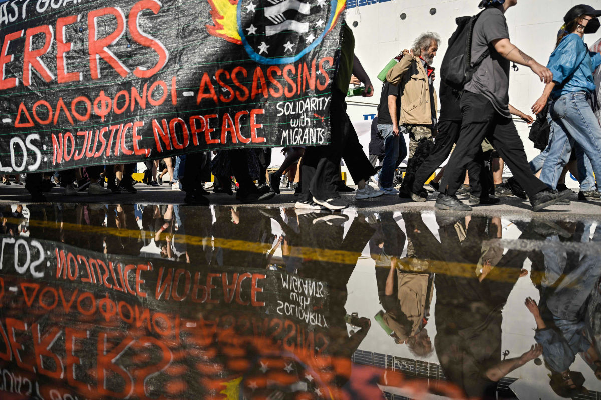Protesters hold a banner during a protest march to the Frontex and Hellenic Coastguard headquarters in the port of Piraeus near Athens, on June 18, 2023, following the deadly shipwreck which costed lives of at least 78 migrants. (AFP)