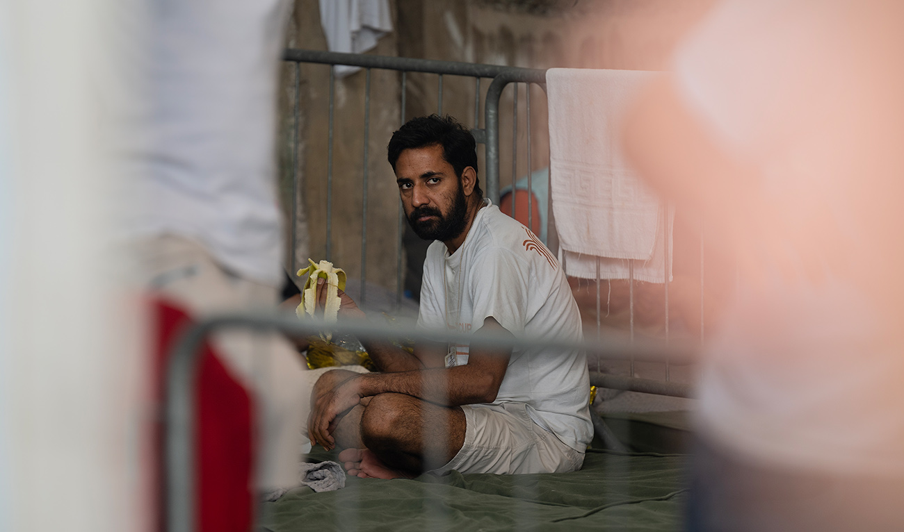 A survivor of a shipwreck sits inside a warehouse at the port in Kalamata town, on June 15, 2023, after a boat carrying migrants sank in international waters in the Ionian Sea. (AFP)