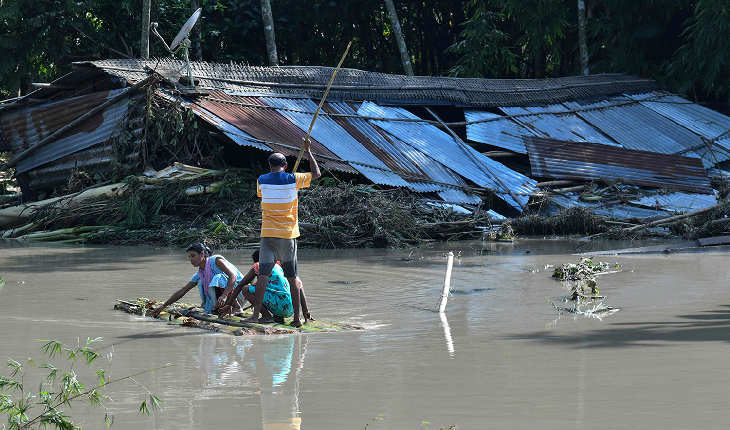 People use a raft to move on a flooded area following monsoon rains in Kenduguri village of Bajali district, some 105 Km from Guwahati in India's Assam state on June 23, 2023. (AFP)