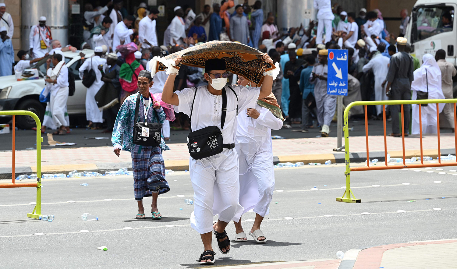 A Muslim pilgrim uses a prayer mat to protect himself from the sun as he walks in Makkah, Saudi Arabia on June 23, 2023. (AFP)