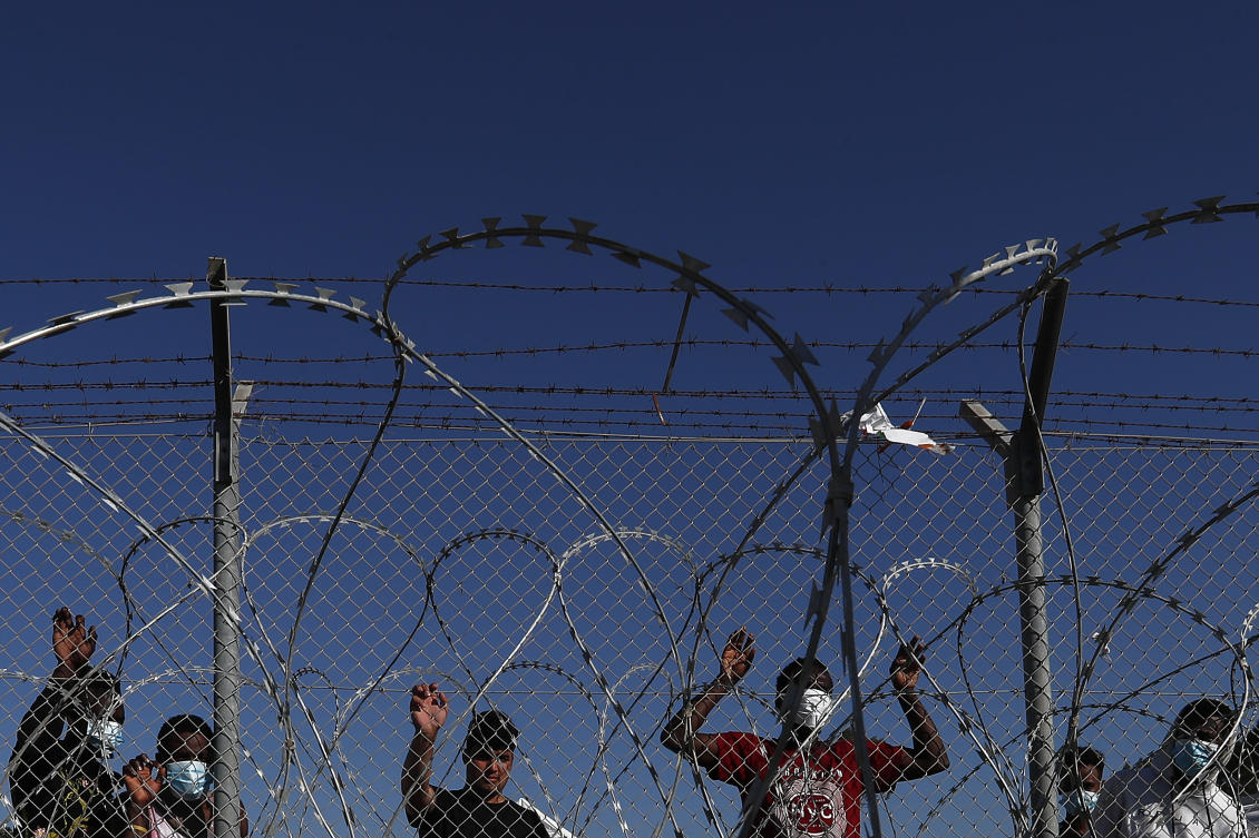 Migrants stand behind a fence inside a refugee camp in Kokkinotrimithia outside of capital Nicosia on Feb. 5, 2021. (AP/File)