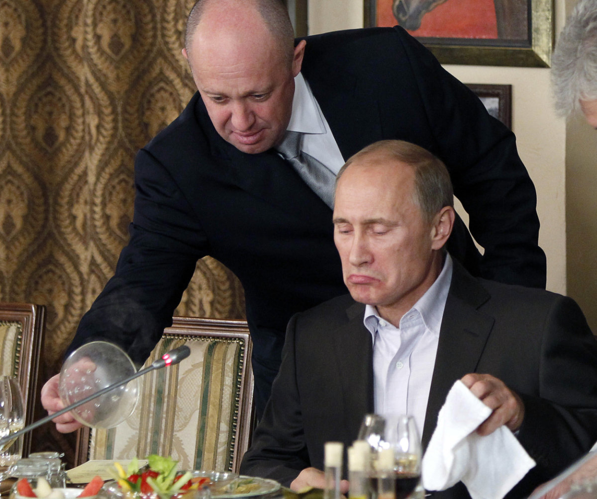 Yevgeny Prigozhin, top, serves food to then-Russian Prime Minister Vladimir Putin at Prigozhin's restaurant outside Moscow on Nov. 11, 2011. (AP Photo, File)