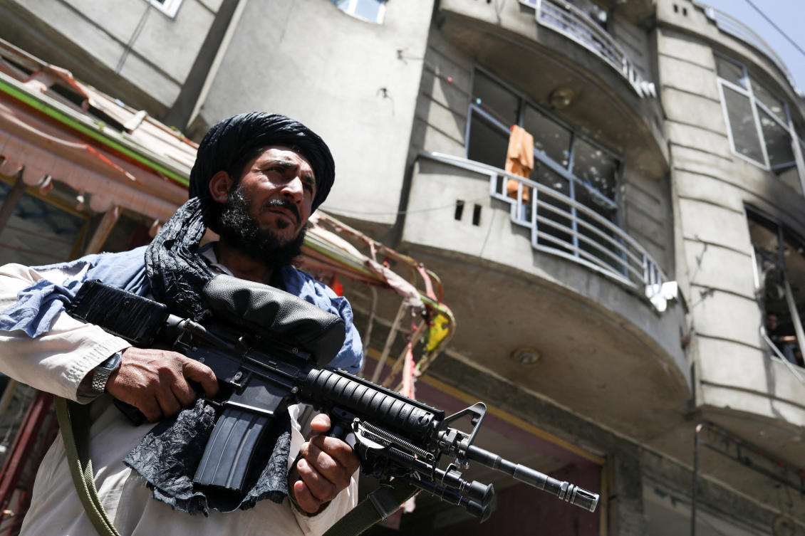 A Taliban fighter stands guard at the site where an explosive-laden vehicle detonated amidst an attack on a Sikh Temple in Kabul on June 18, 2022. (Reuters)