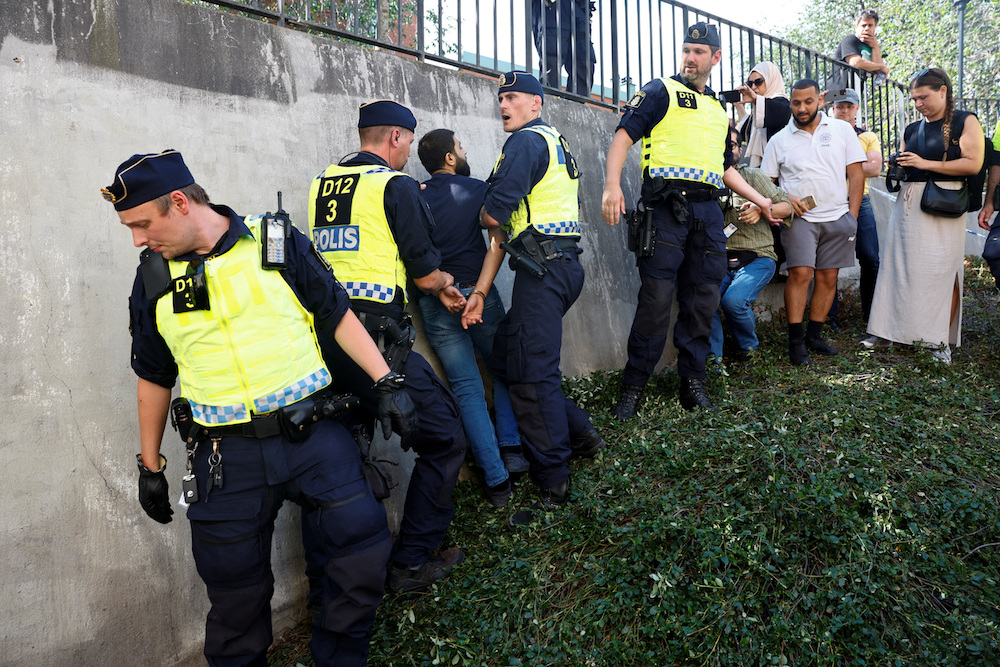 Police officers intervene after people's reaction as demonstrators burn the Qur’an (not pictured) outside Stockholm's central mosque in Stockholm, Sweden June 28. (Reuters)