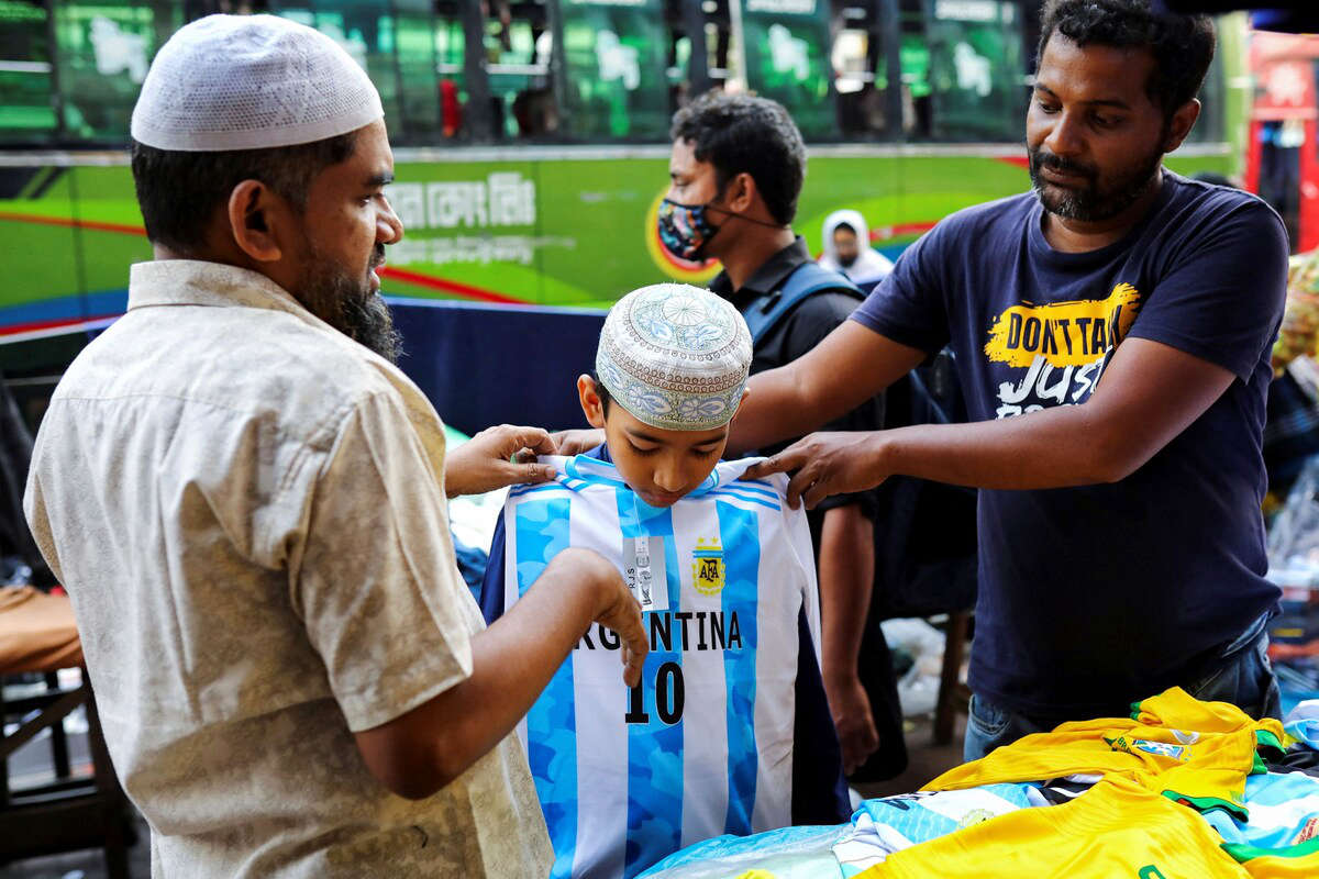 A young fan of Argentina tries a jersey from a street shop ahead of the FIFA World Cup, in Dhaka, Bangladesh, Nov. 16, 2022. (Reuters)