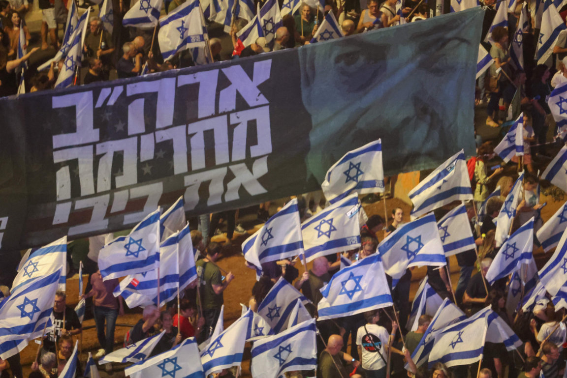 Demonstrators lift banners and flags during a rally in Tel Aviv to protest Israeli government’s judicial overhaul plan. (AFP)