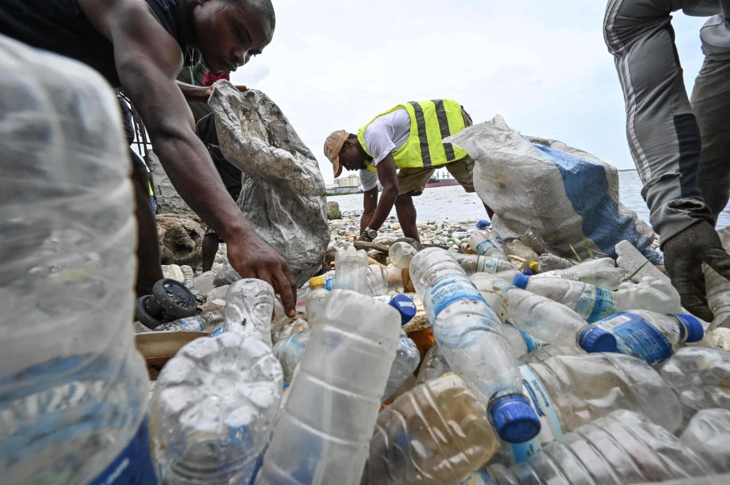 Residents collect plastics bottles in the Ebrie Lagoon in Abidjan on May 31, 2023 ahead of World Environnement Day. (AFP)